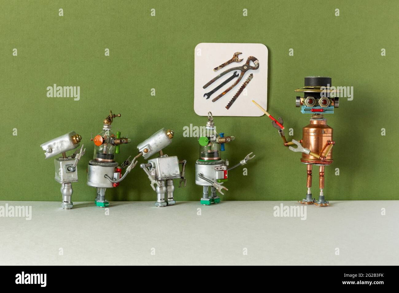 Una guía robótica explica a los jóvenes visitantes de la exposición la  historia de las herramientas mecánicas. Los estudiantes de robots estudian  una vieja fotografía en el verde Fotografía de stock -