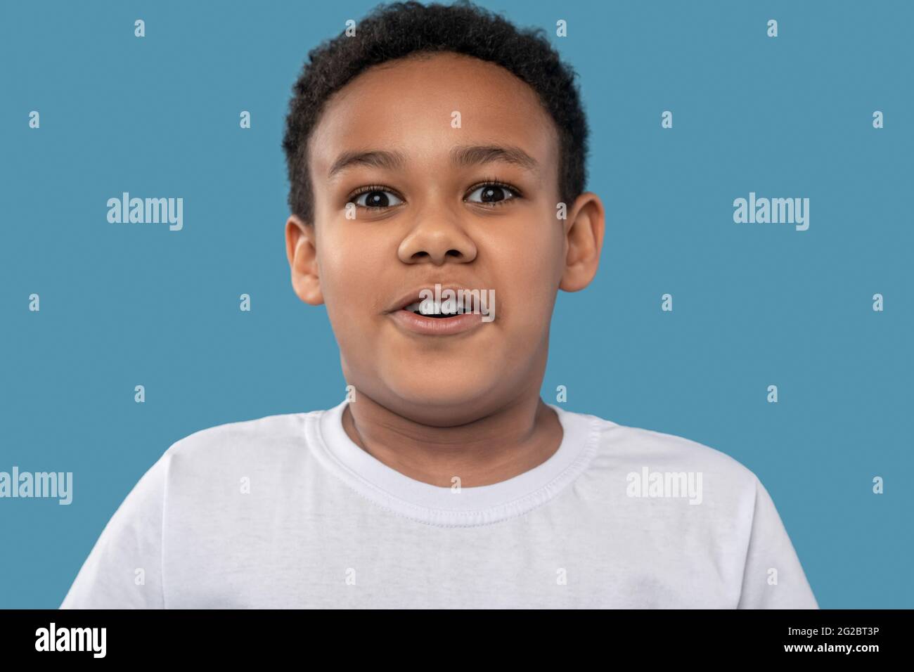 Sorprendido niño africano americano encantado sobre fondo azul Foto de stock