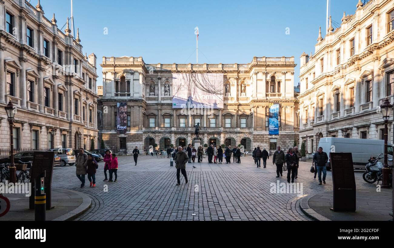 La Real Academia de las Artes, Londres. Visitantes en el patio central de la RA con carteles de exposición para Anthony Gormley y Lucian Freud visible. Foto de stock
