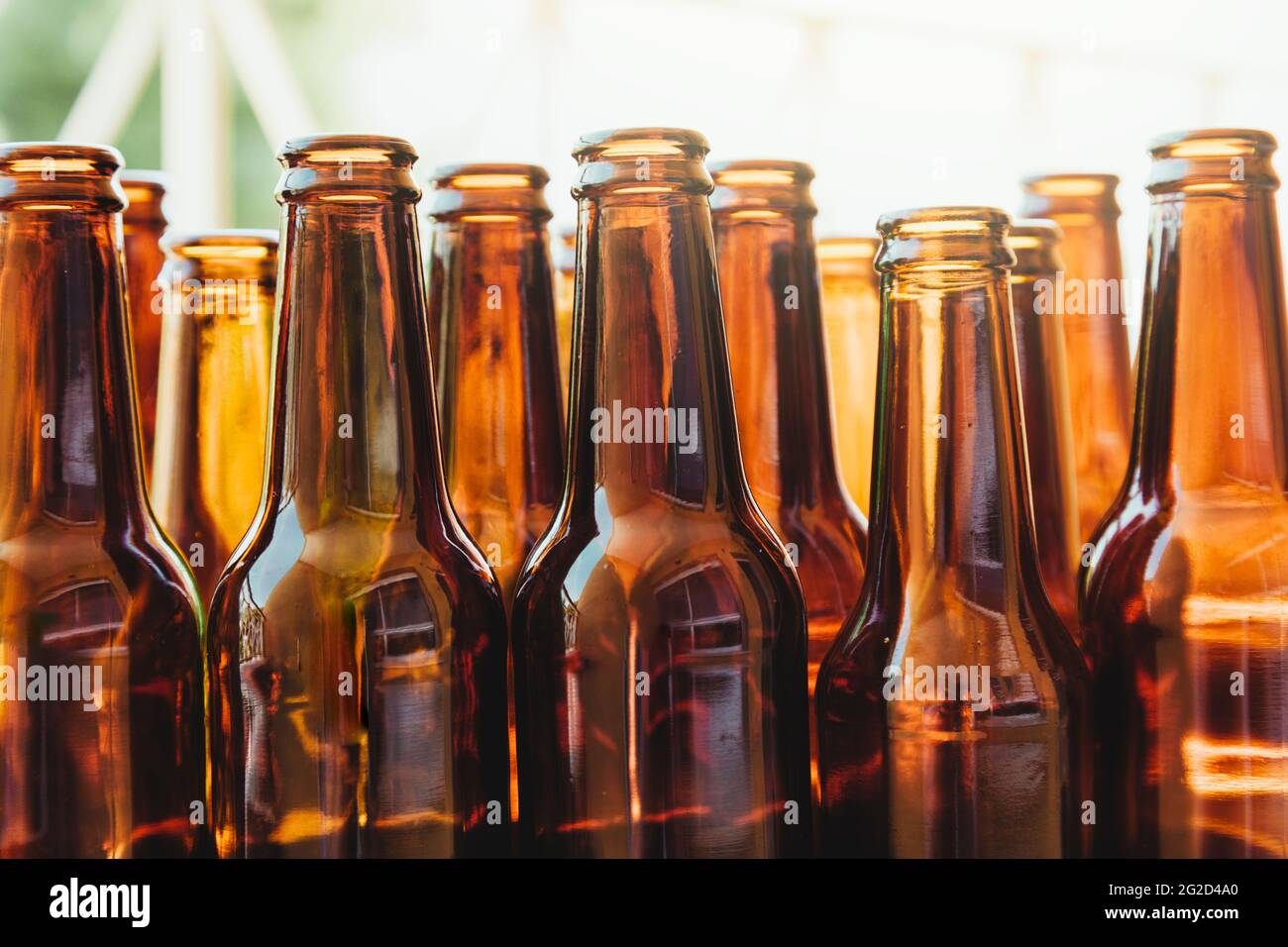 Varias botellas de vidrio marrón vistas desde un ángulo bajo. Una gran cantidad de luz entra detrás de las botellas. Foto de stock