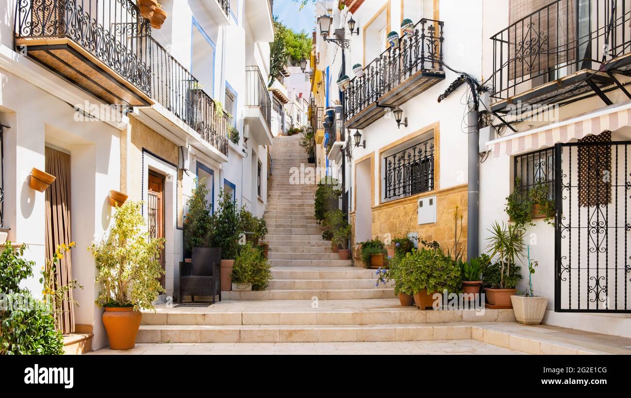 Calle estrecha con escalones, casas blancas y plantas en macetas en el  antiguo barrio El Barrio o Casco Antiguo Santa Cruz en Alicante casco  antiguo de la ciudad Fotografía de stock -