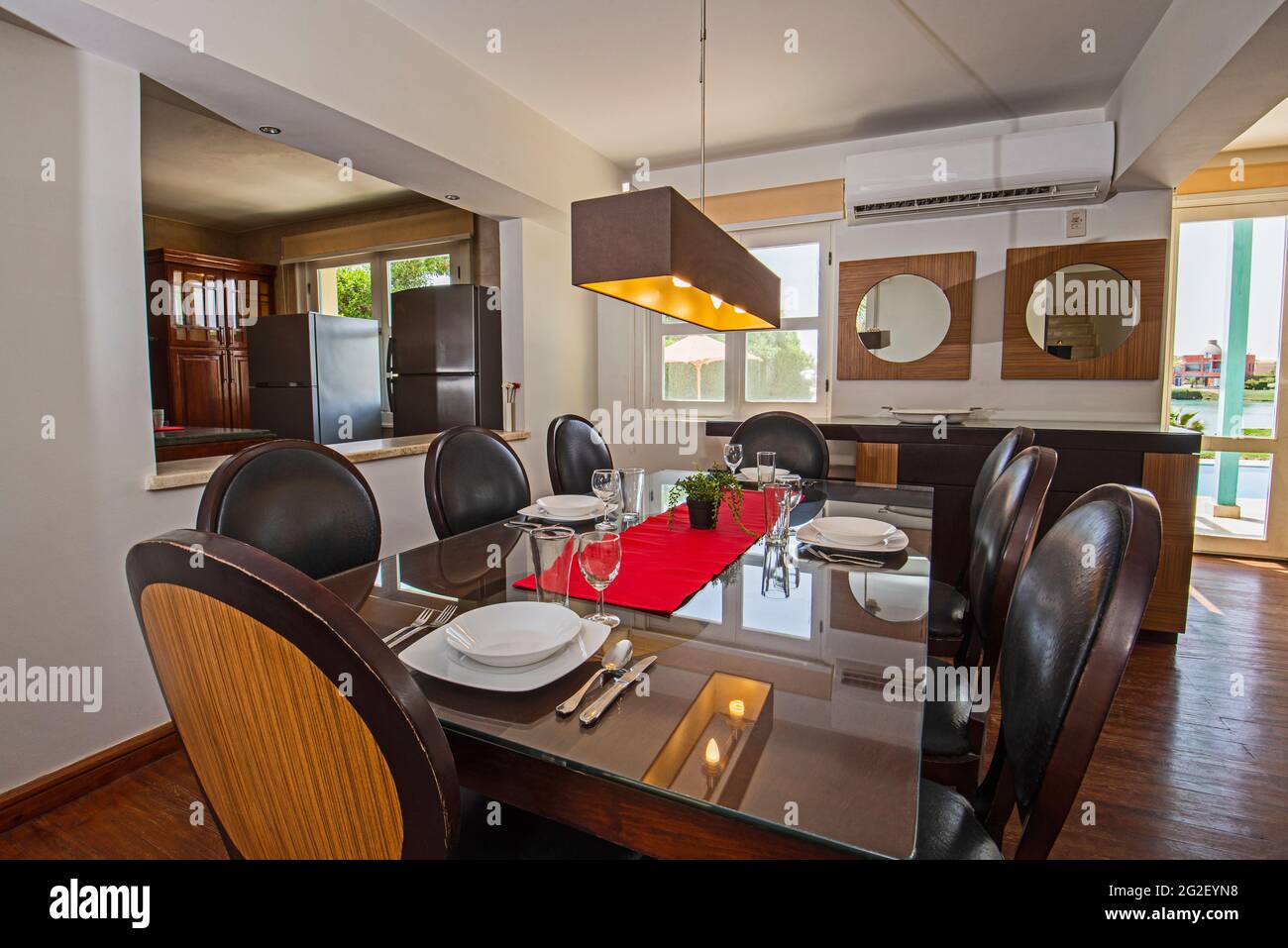 Zona de comedor en villa de lujo de vacaciones mostrar casa con diseño interior decoración muebles con mesa de diseño y cocina de planta abierta Foto de stock