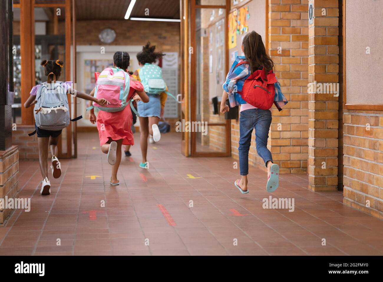 Vista trasera del grupo de niñas corriendo en el pasillo de la escuela Foto de stock