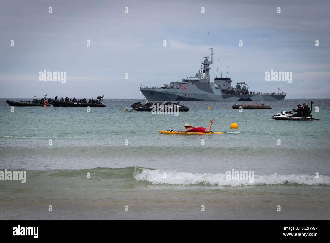 St Ives, Reino Unido. 11th de junio de 2021. Un barman nadará más allá de la Marina Real que ha sido desplegada para la Cumbre de G7. Crédito: Andy Barton/Alamy Live News Foto de stock