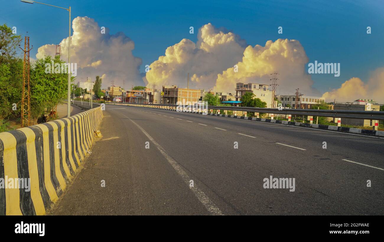 25 de mayo de 2021 - Reengus, Sikar, India. Impresionante tiro de carretera con barrera de seguridad de metal o carril. Coches en el asfalto bajo el cielo nublado. Foto de stock