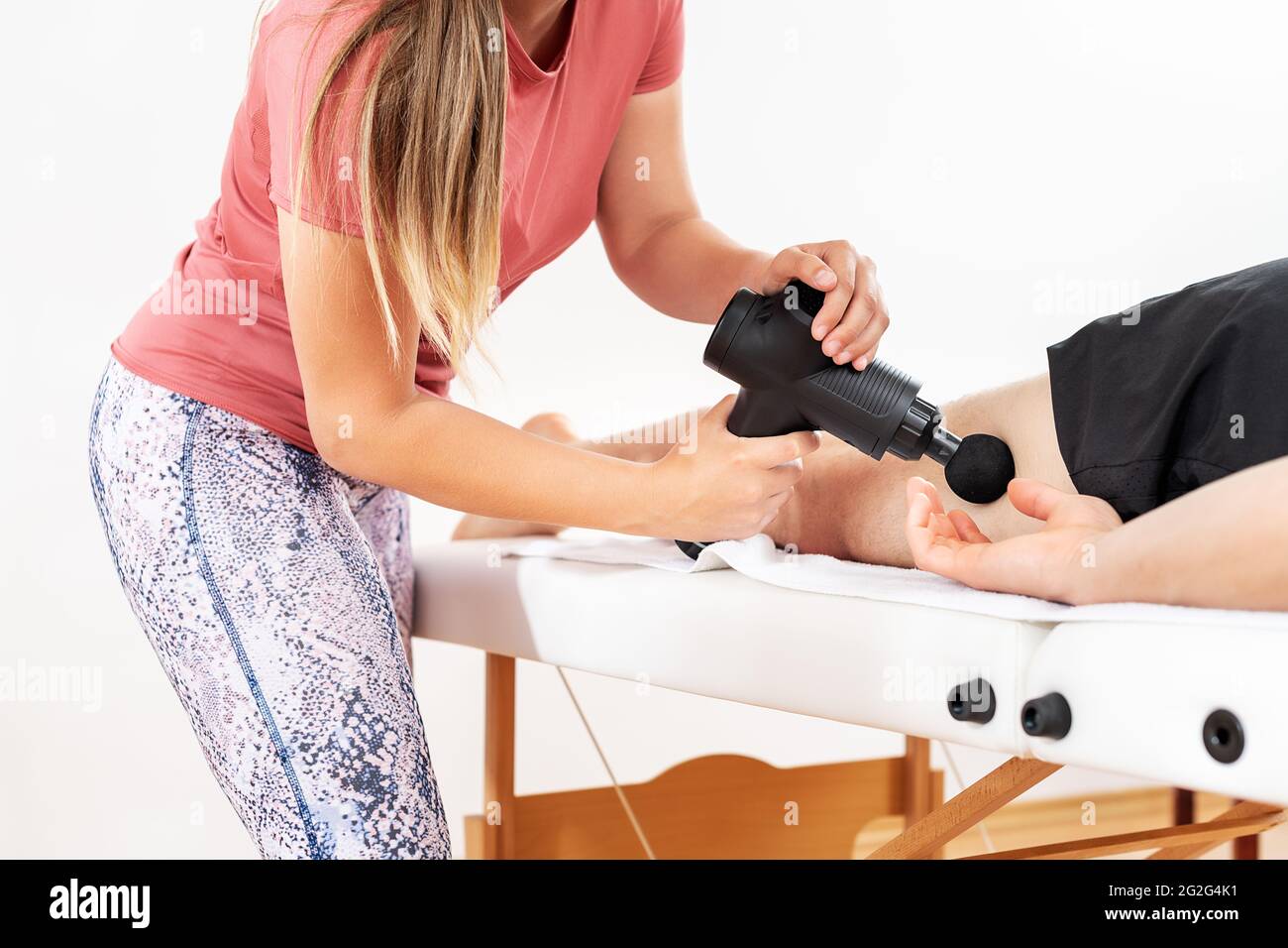 https://c8.alamy.com/compes/2g2g4k1/pistola-de-masaje-fisioterapeuta-femenina-joven-que-utiliza-una-pistola-de-masaje-manual-para-aliviar-el-dolor-muscular-de-las-piernas-durante-la-sesion-de-fisioterapia-2g2g4k1.jpg