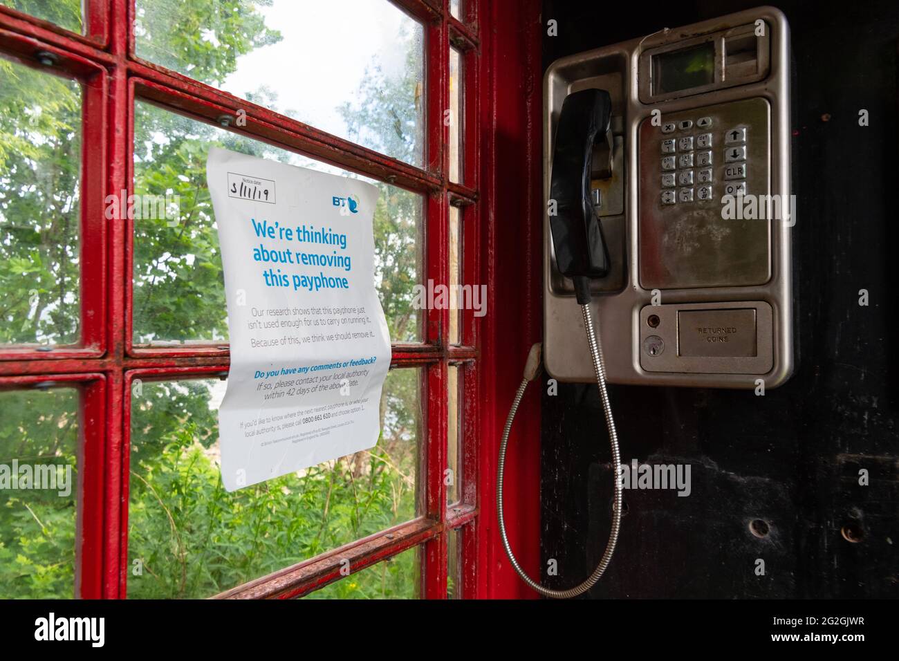 'Estamos pensando en eliminar este teléfono público' en el interior de la caja de teléfono bt roja tradicional, Strachur, Argyll y Bute, Escocia, Reino Unido Foto de stock
