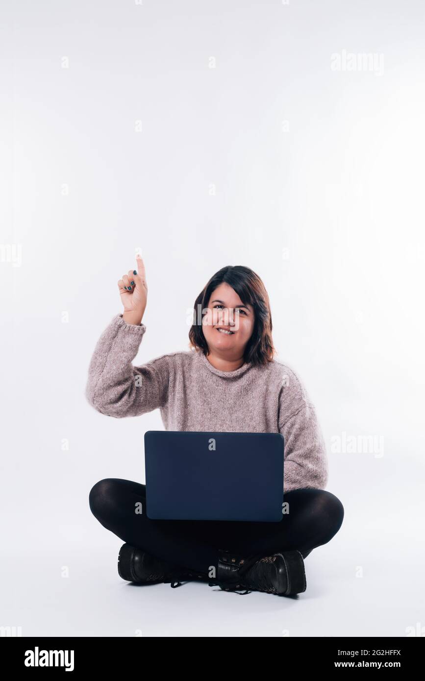 Imagen vertical de una mujer sentada con el portátil apuntando hacia arriba. Espacio de copia Foto de stock