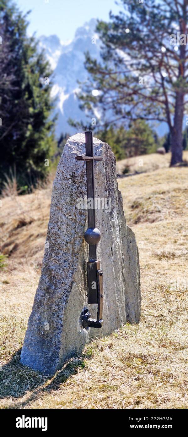 La piedra memorial se levanta sin letras con una simple cruz de metal en el borde del bosque. Se desconoce la causa y la razón Foto de stock
