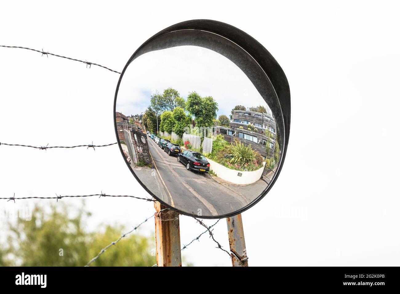 Un espejo de visión de tráfico en postes metálicos con protección de alambre de púas. Foto de stock