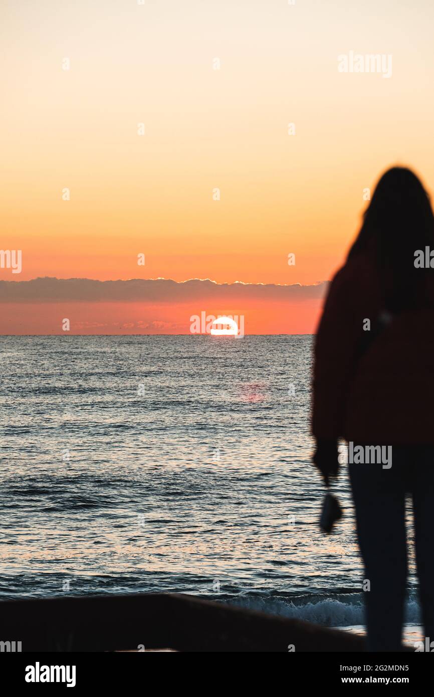 Chica mirando el amanecer frente al mar en Barcelona, España Fotografía de  stock - Alamy