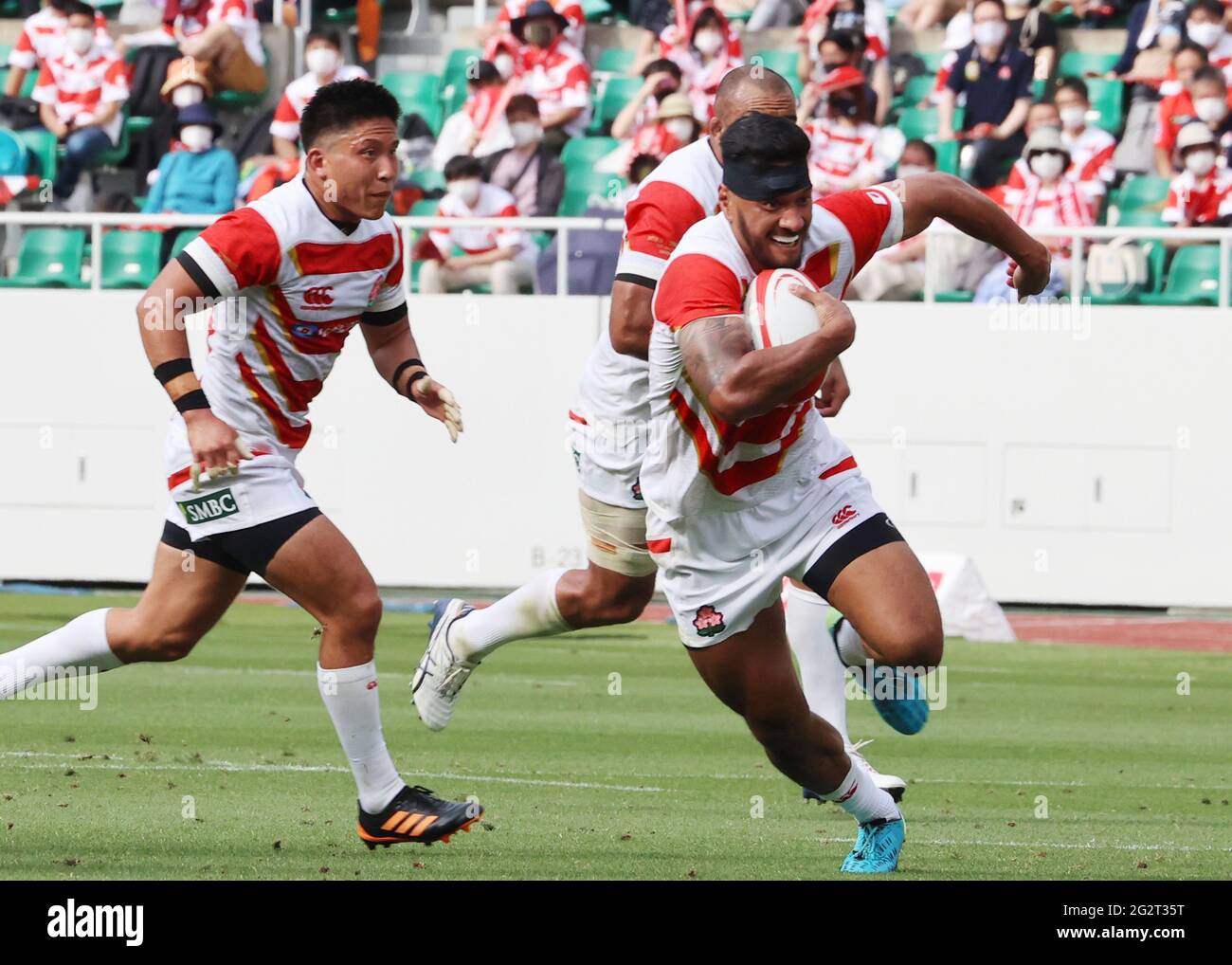 Fukuroi, Japón. 12th de junio de 2021. Timothy Lafaele lleva el balón en el  centro de la selección nacional de rugby de Japón, mientras que la mitad  del scrum Kato Shigeno (L)