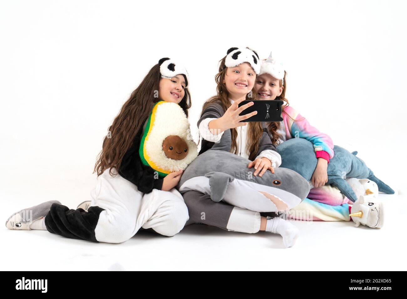 Lindas chicas adolescentes en kigurumi y máscaras de sueño sonriendo y dispara un vídeo. Selfies. Foto de stock