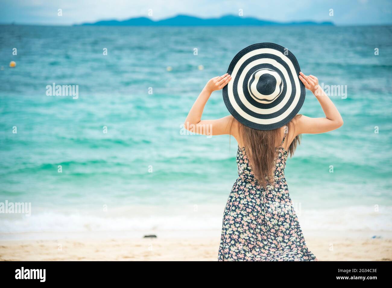 Vacaciones de verano para mujeres bronceadas en la playa. Alegre mujer  vestir vestido de verano y sombreros de paja sentado en la playa mirar al  mar. Tiempo para relajarse en verano Fotografía