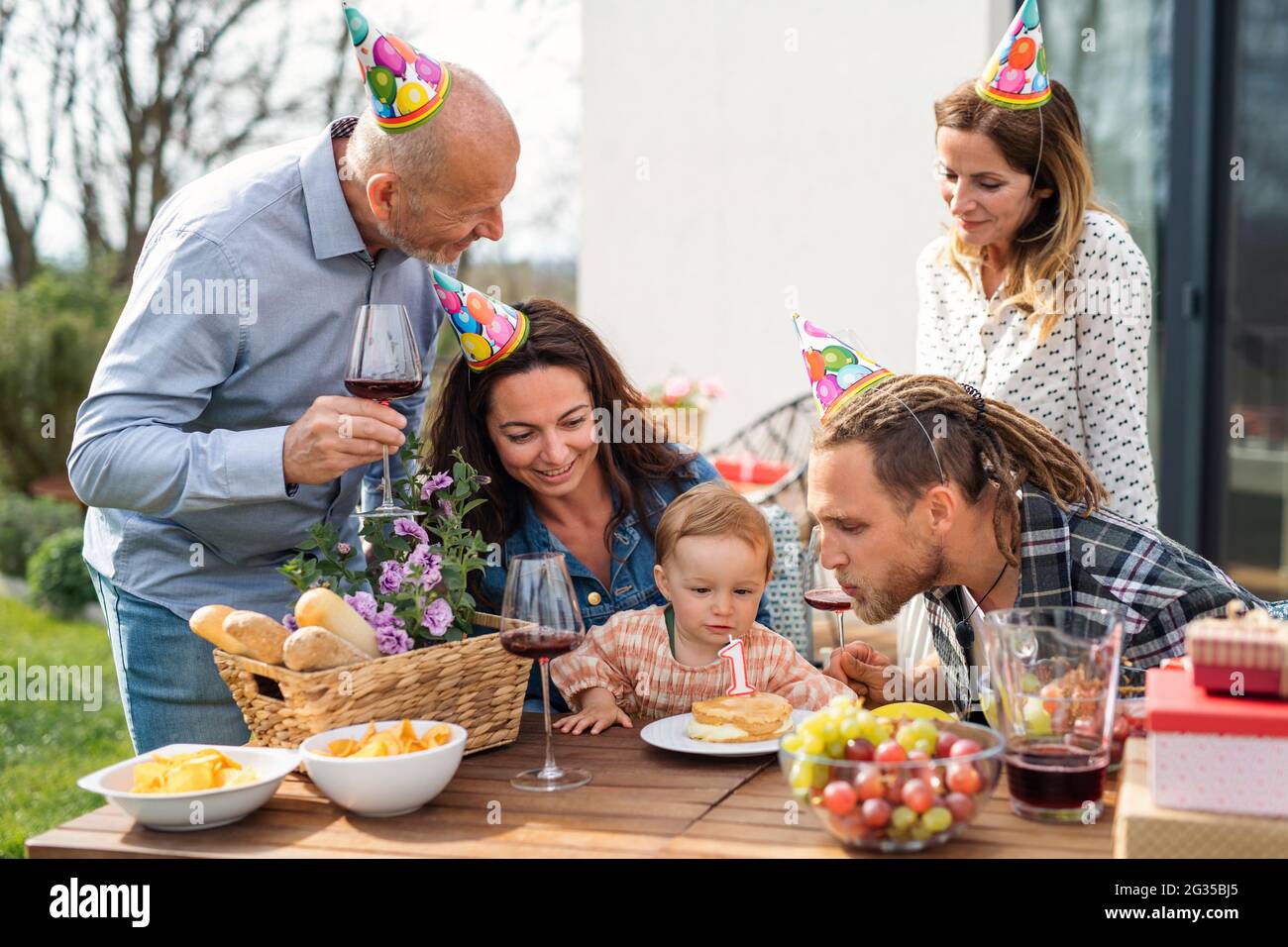 Feliz familia de varias generaciones al aire libre en el jardín en casa, fiesta de cumpleaños. Foto de stock