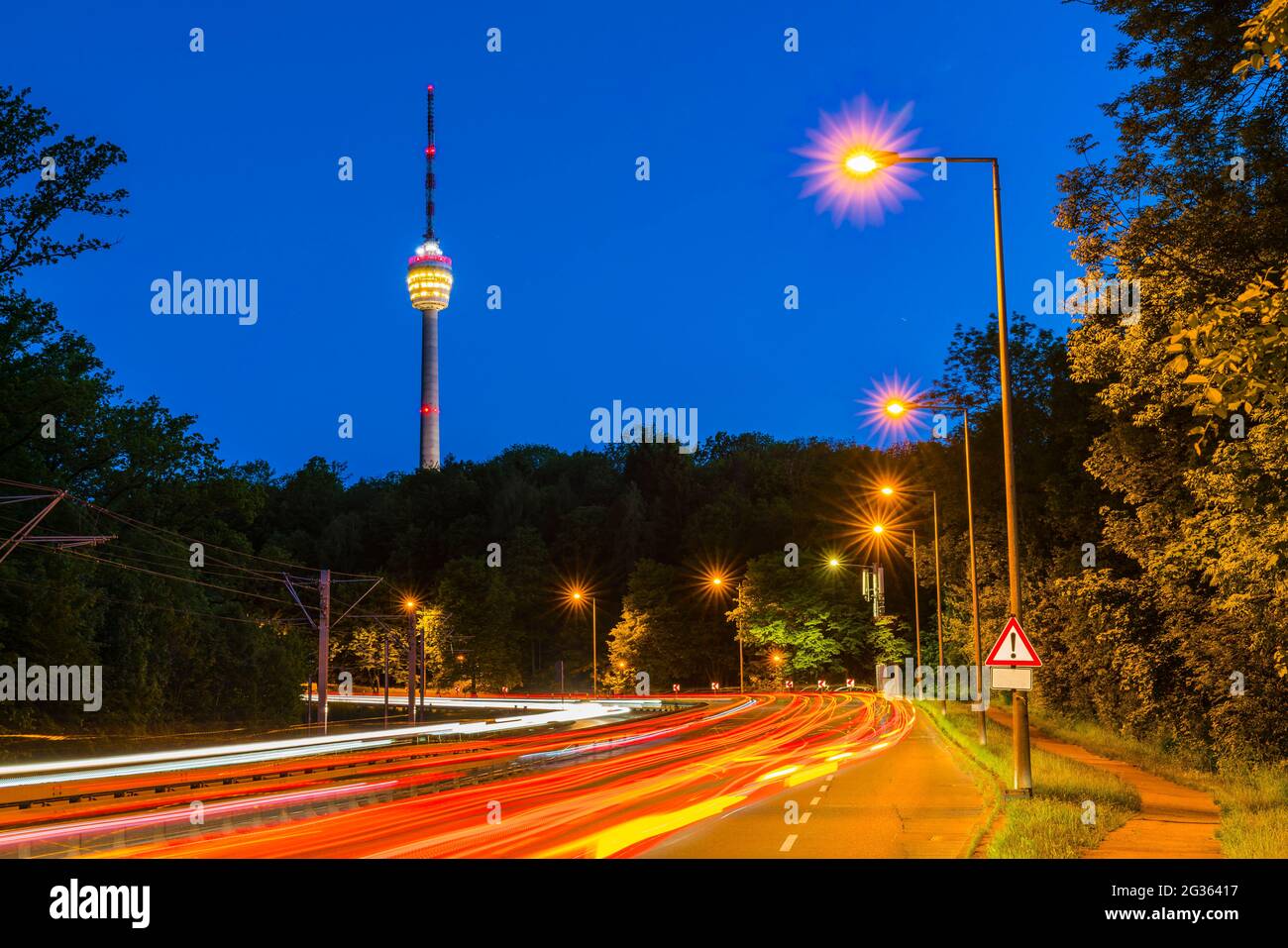 Alemania, el horizonte urbano de Stuttgart y la autopista con tráfico de coches por la noche iluminando la calle que conduce a la torre de televisión llamada fernsehturm Foto de stock