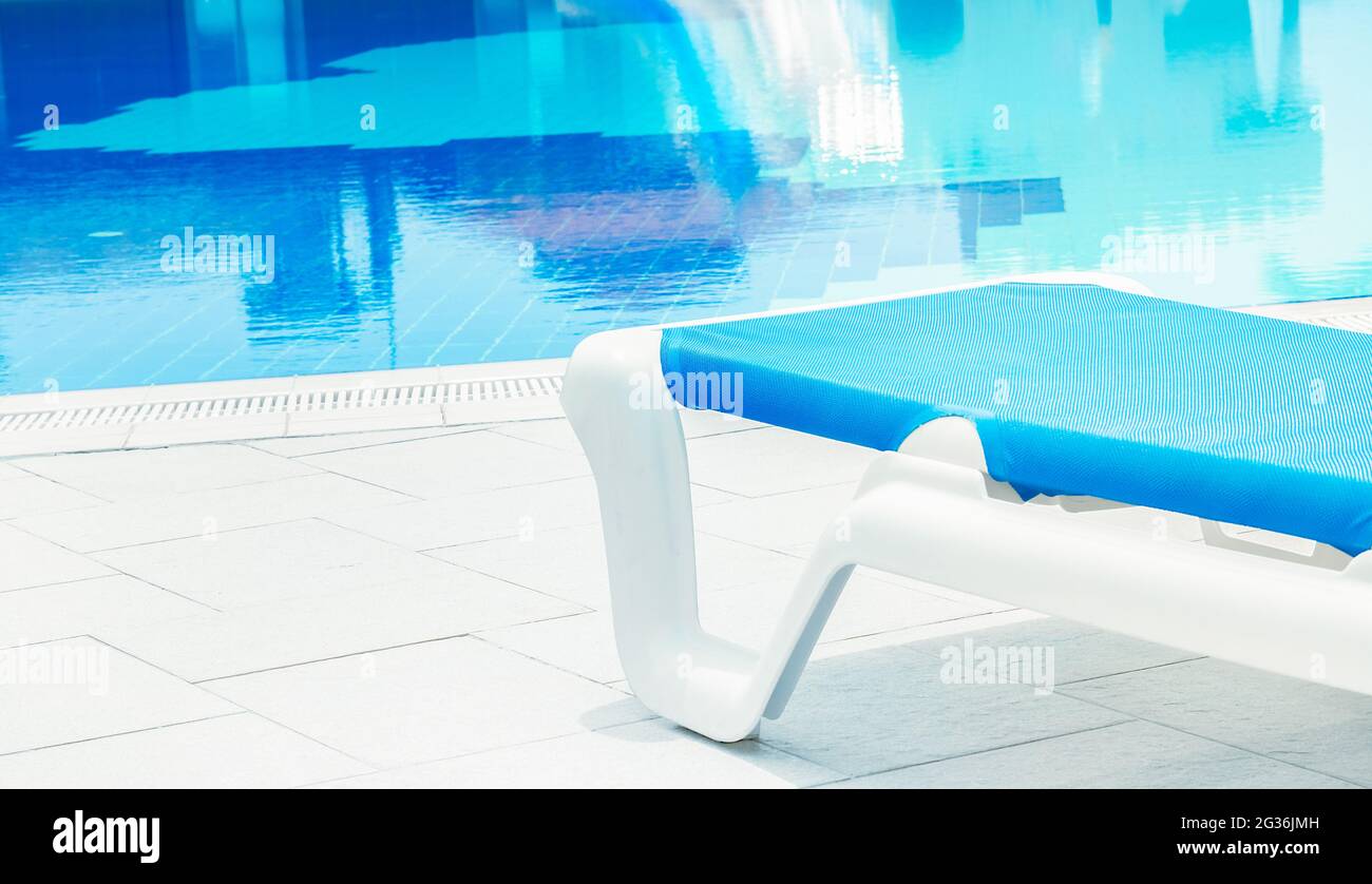 Detalle de primer plano de una tumbona blanca junto a la piscina en un caluroso día de verano. Concepto de destino de vacaciones de verano. Foto de stock