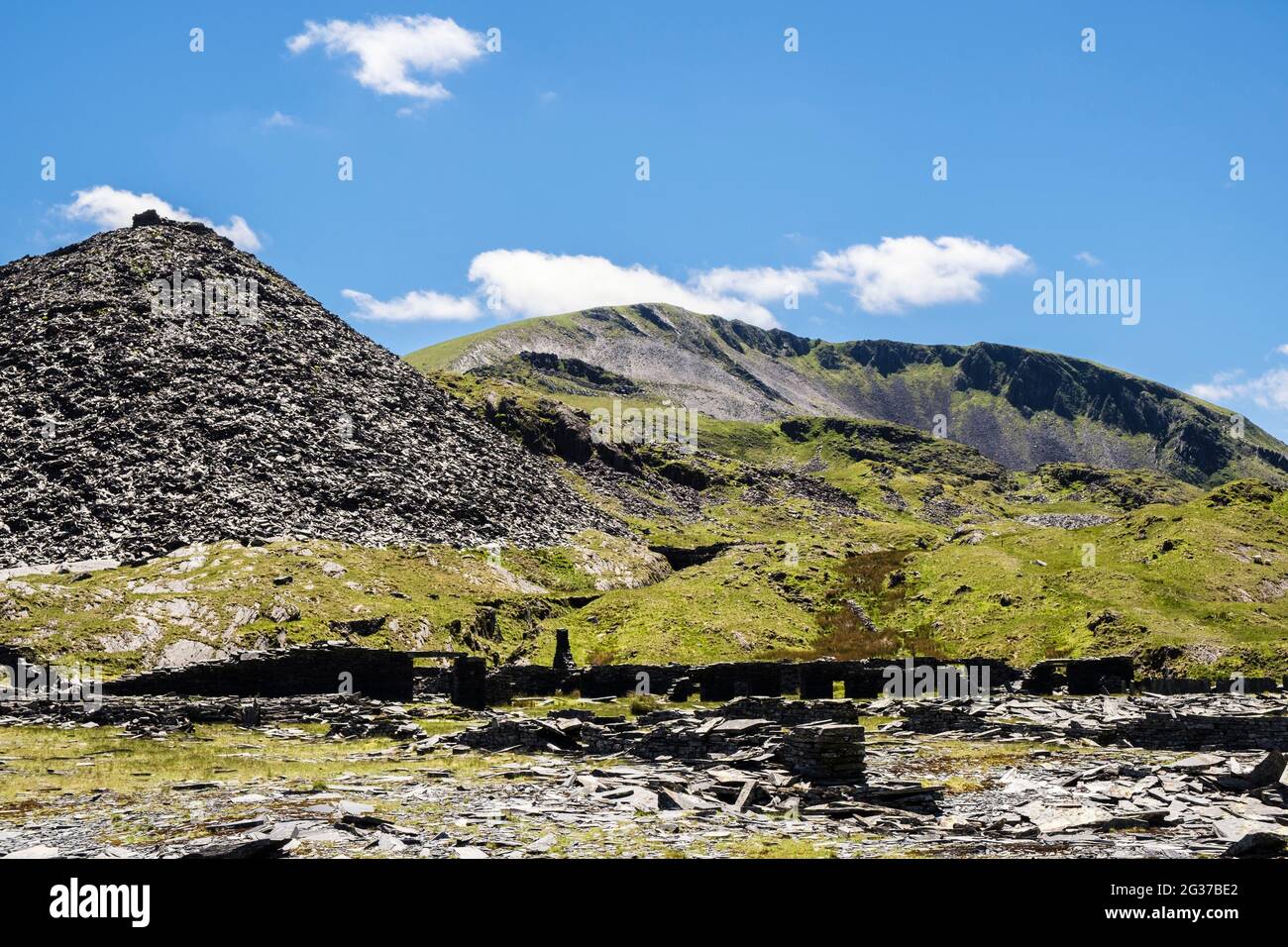 Antiguas ruinas abandonadas y un montón de escorias en la cantera de pizarra de Rhosydd con Moelwyn Mawr más allá en el Parque Nacional de Snowdonia. Croesor Bleanau Ffestiniog Gwynedd Gales Foto de stock
