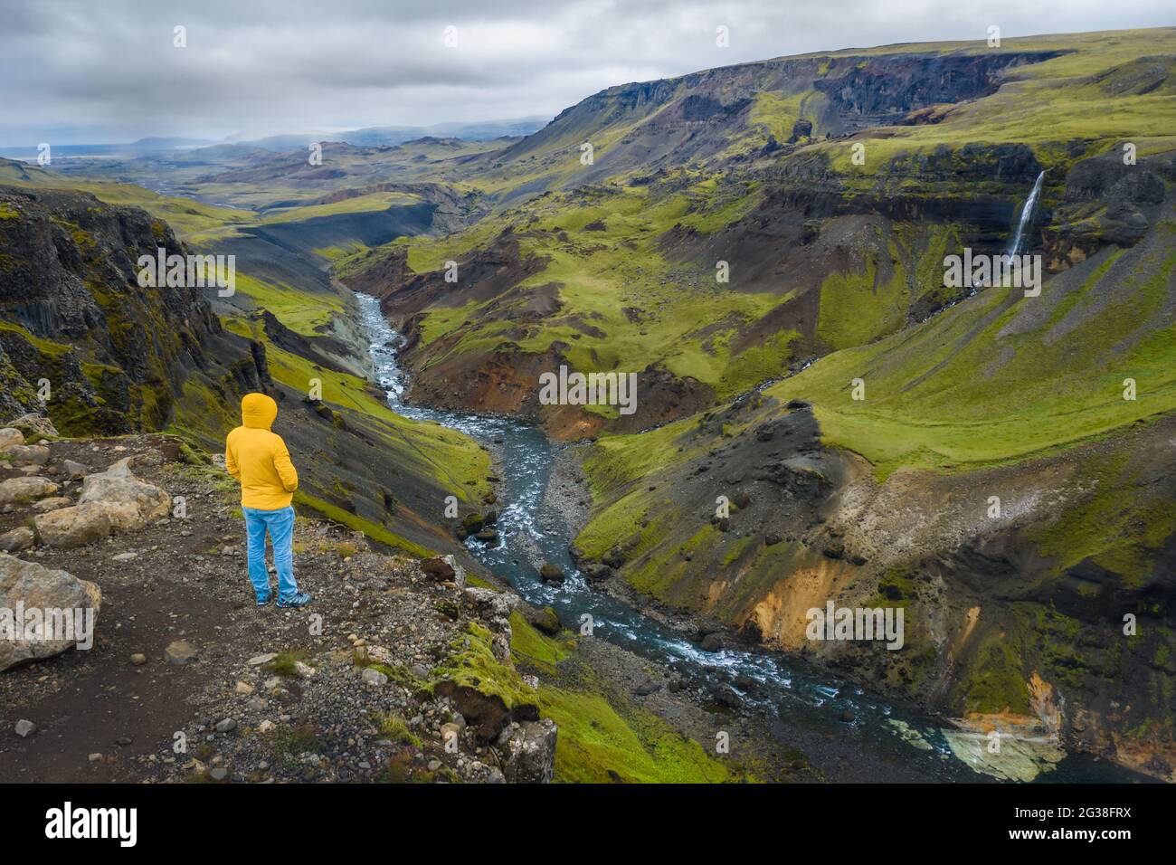 Vista aérea del hombre disfrutando del paisaje de Islandia del valle de las tierras altas y el río Fossa con el arroyo de agua azul y colinas verdes y acantilados cubiertos de musgo. Foto de stock