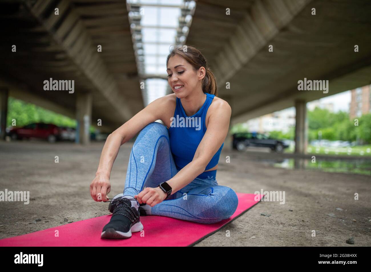 Mujer atlética atando sus zapatillas sentadas en el piso del gimnasio. Mujer  atlética atando sus zapatillas en el gimnasio Fotografía de stock - Alamy