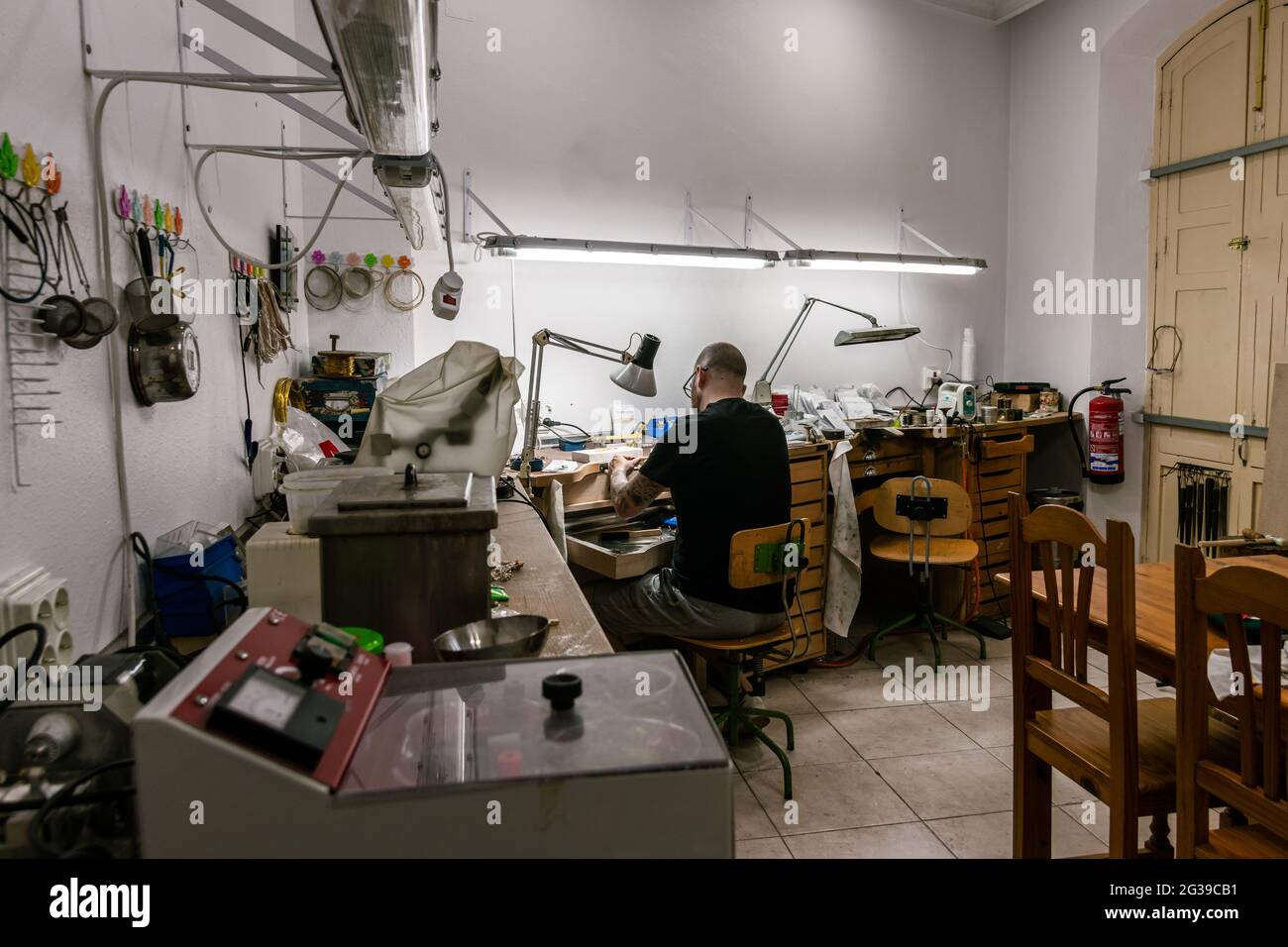 Taller de joyería con un hombre trabajando en el fondo Fotografía de stock  - Alamy