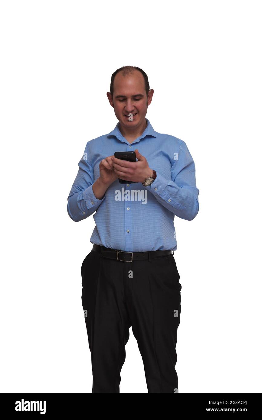 Hombre calvo vestido con camisa azul y pantalones negros tocando la pantalla táctil de su smartphone aislado sobre fondo blanco. Puede ser un trabajador de oficina o banquero Foto de stock