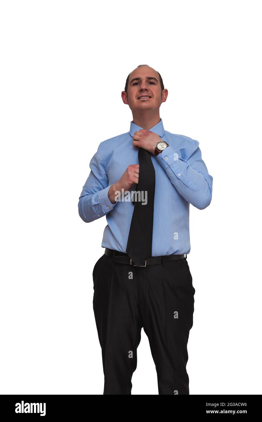 Hombre calvo vestido con camisa azul y pantalones negros que ajustan nudo con manos de corbata negra aisladas sobre fondo blanco. Puede ser trabajador de oficina, jefe o banco Foto de stock