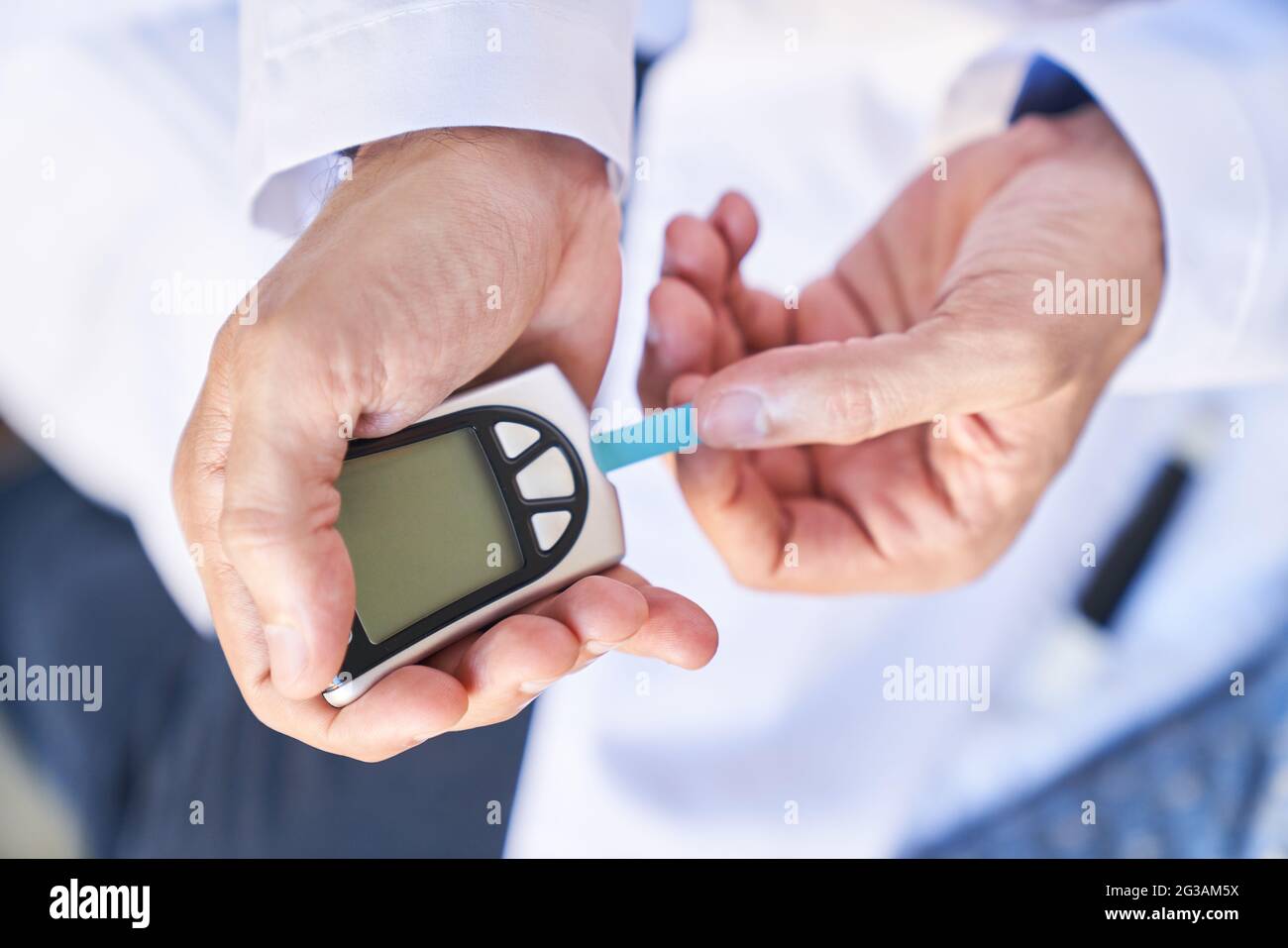 Medidor de glucosa en sangre en la mano sobre fondo azul.