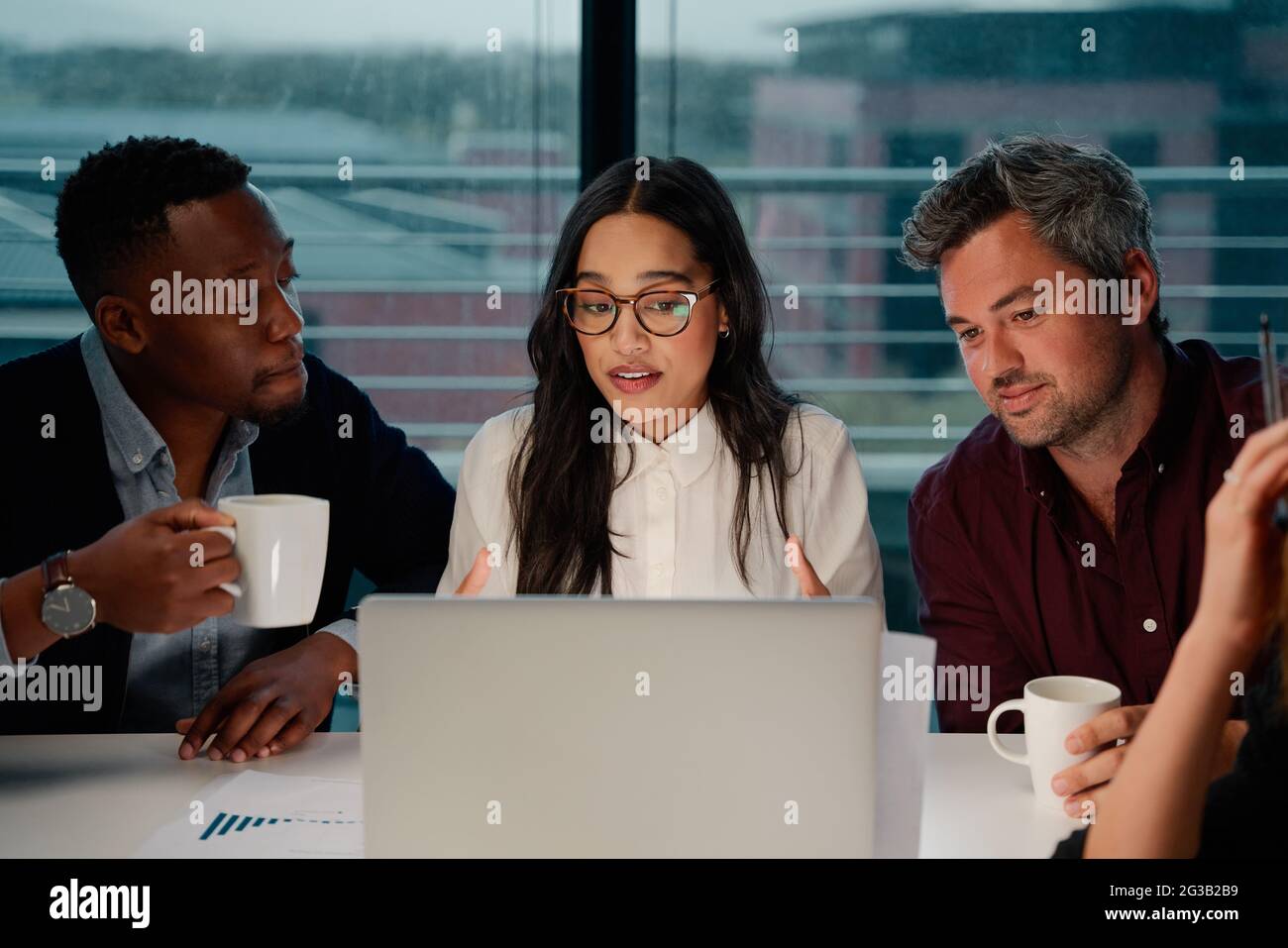 Los colegas masculinos escuchan a la empresaria explicar la estrategia en el negocio corporativo usando el portátil Foto de stock
