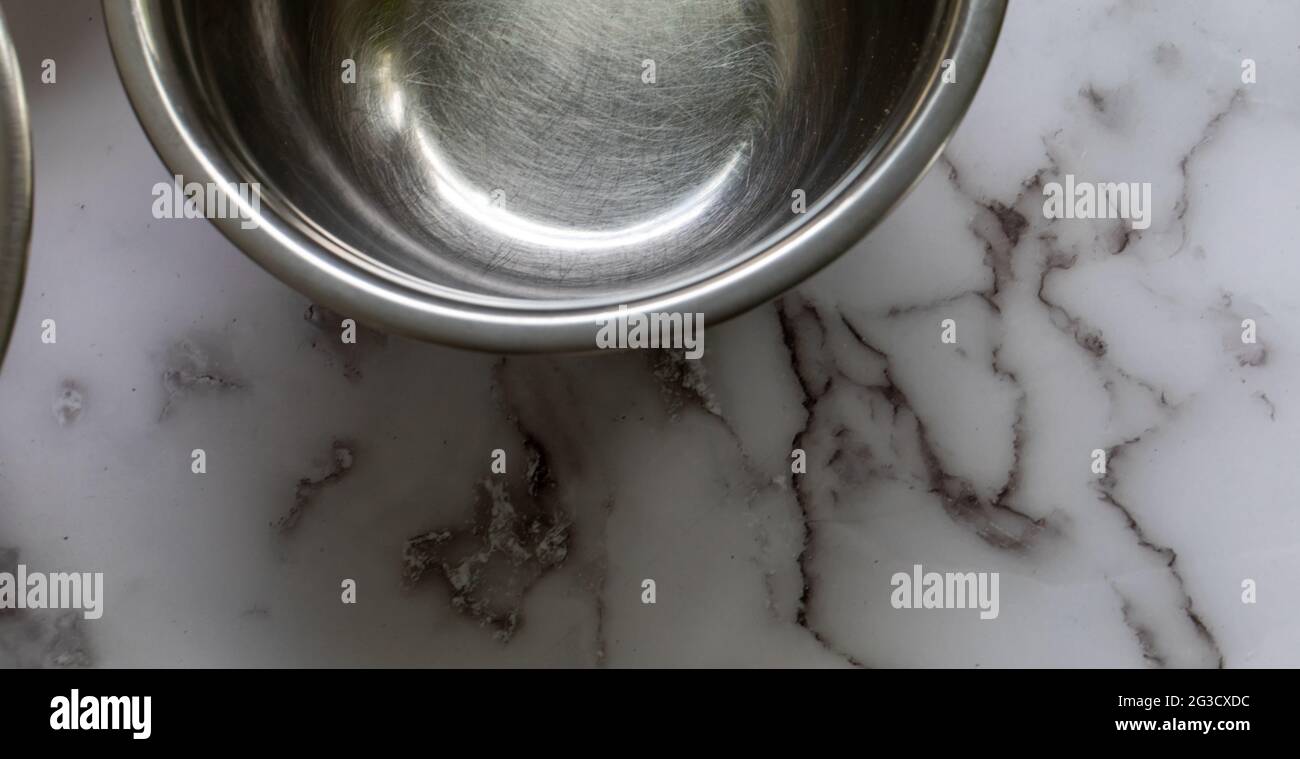 media vista de un vacio tazón de mezcla redondo de metal sobre una superficie de mármol con luz natural Foto de stock