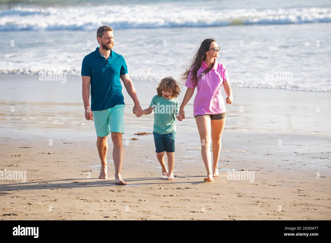 Familia caminando por la playa. Madre padre e hijo pasando tiempo juntos.  Vacaciones de verano en familia. Padre papá mamá caminando con el hijo  sostiene la mano Fotografía de stock - Alamy