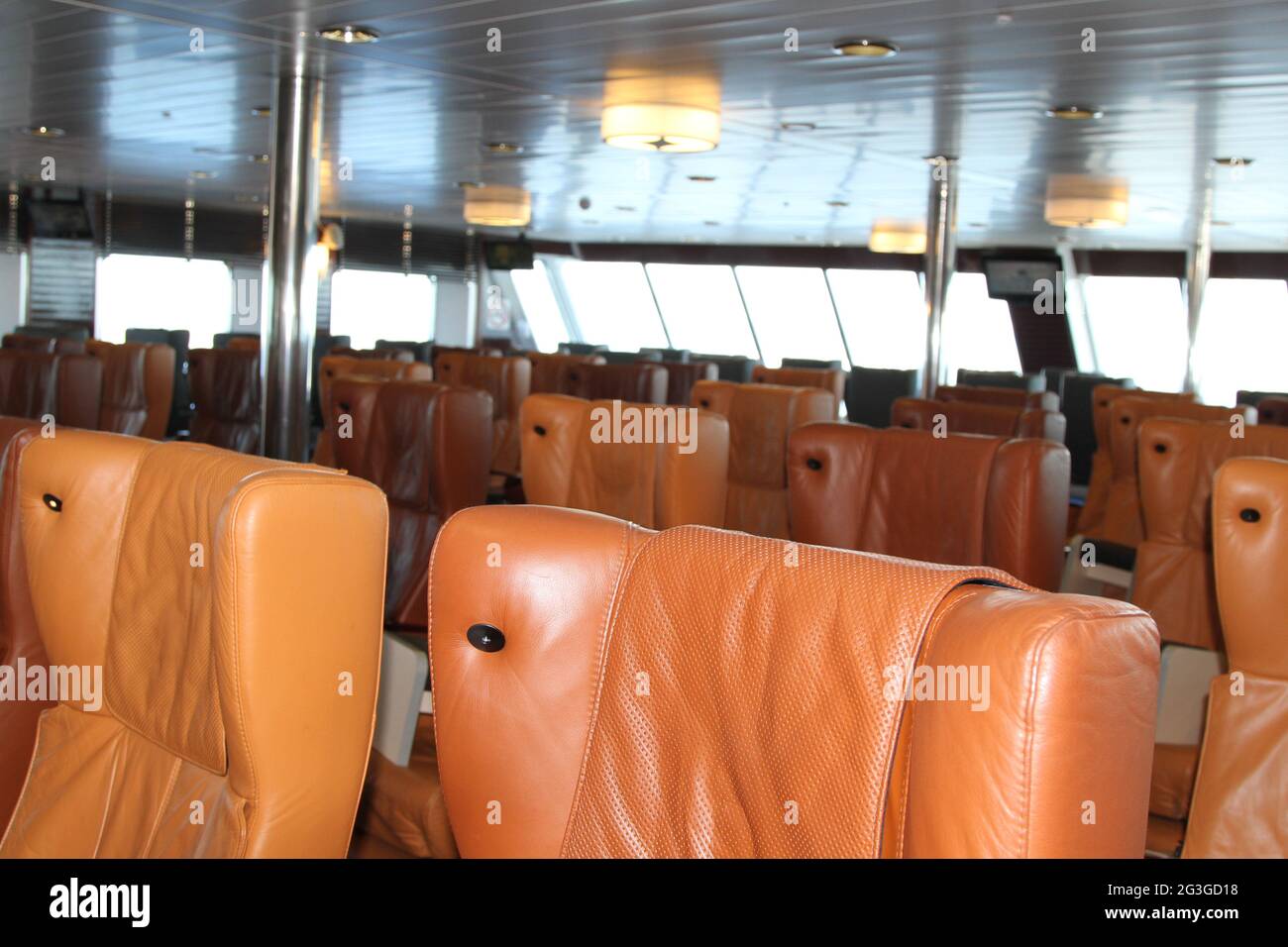 Interior del ferry con asientos de cuero naranja e iluminación superior Foto de stock