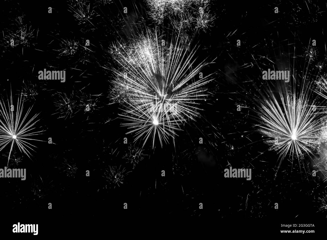Fuegos artificiales blancos y negros a través de un cielo nocturno negro Foto de stock
