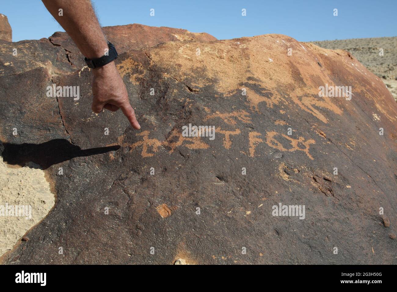 La mano del hombre apunta a antiguas tallas de roca de probablemente una forma temprana no identificada de letras árabes escritas hace 2000 años por los jinetes de camellos de Nabateans Foto de stock