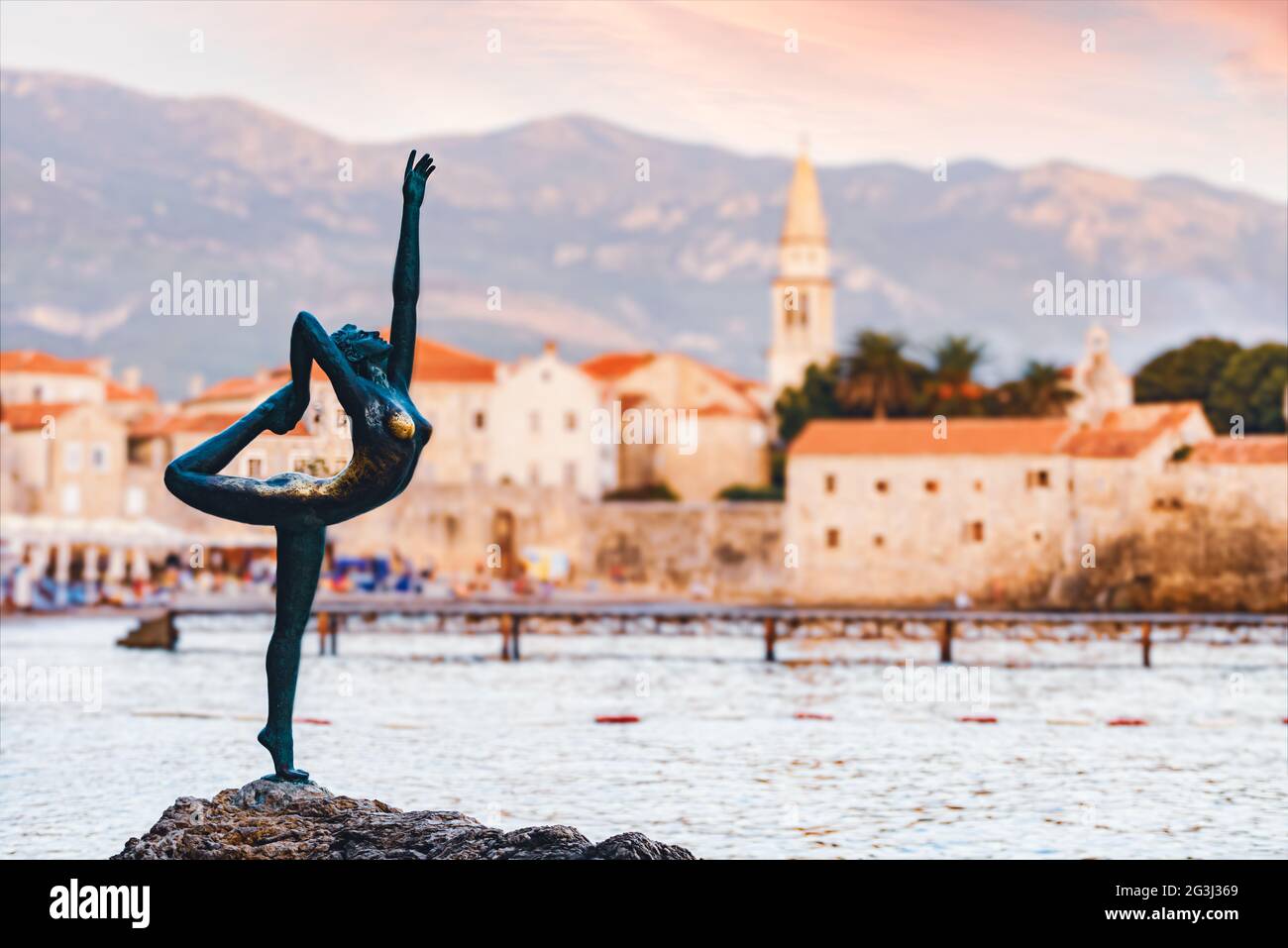 Escultura de bailarina en Budva, Montenegro, Balcanes, Europa. Casco antiguo y montañas en la parte trasera. Foto de stock