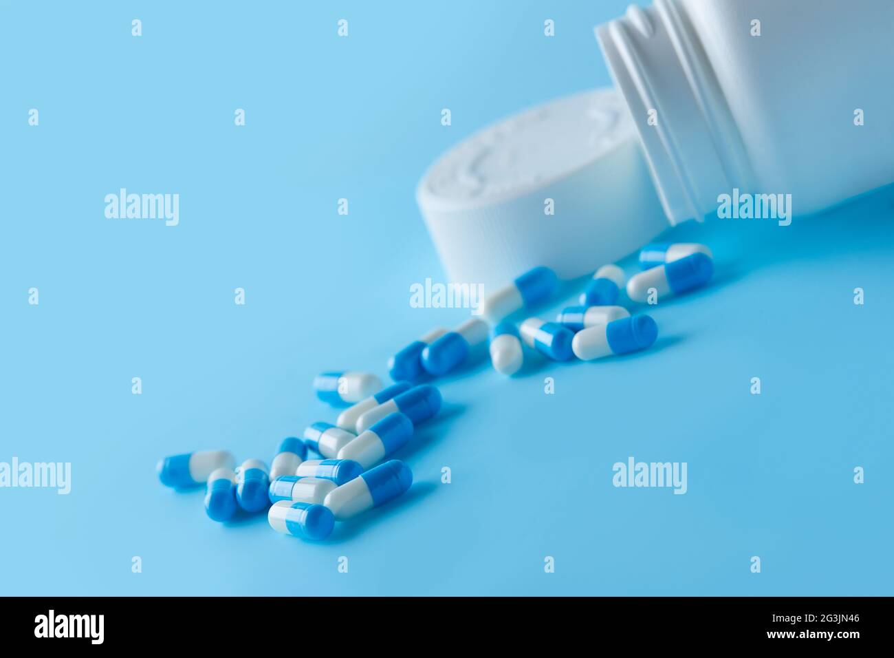 Muchas cápsulas blancas y azules se propagan sobre fondo azul Antibióticos resistencia a los medicamentos. Pastillas de cápsula antimicrobiana. Industria farmacéutica. Global Foto de stock