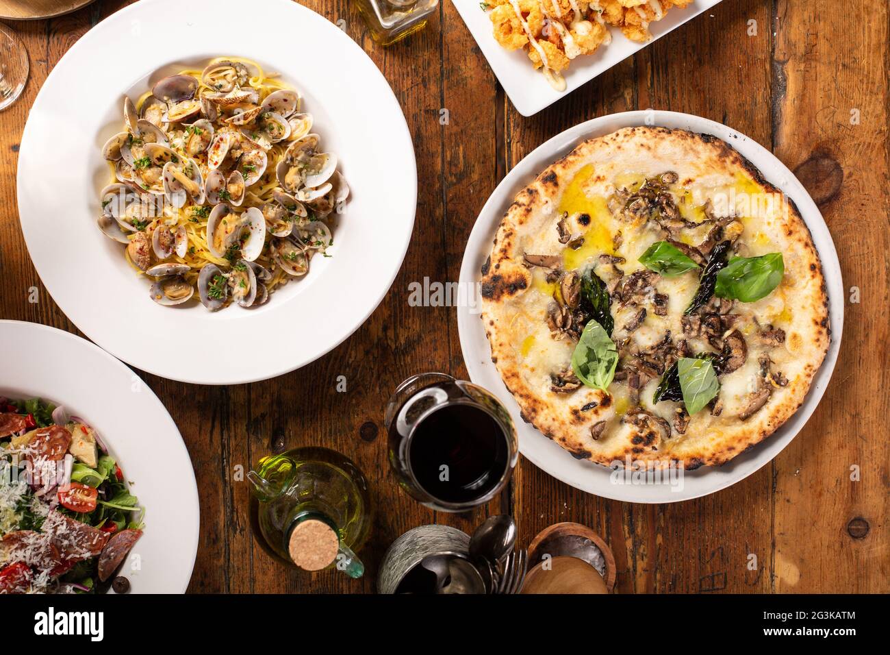 Pizza y pasta sobre mesa de madera con vino Foto de stock