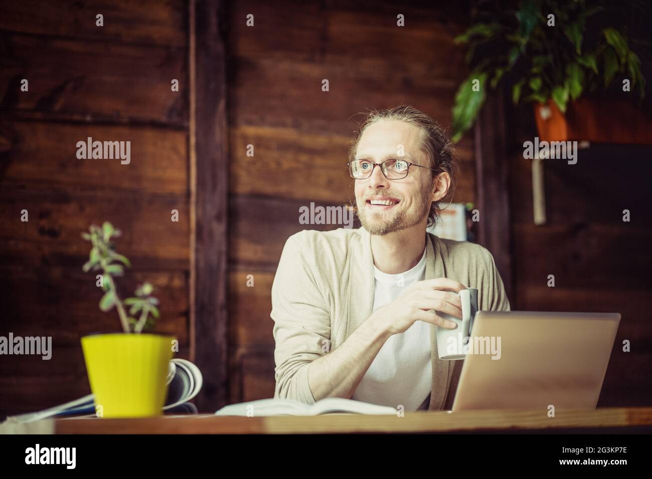 Freelancer trabajando, bebiendo té, mirando a un lado. Foto de stock