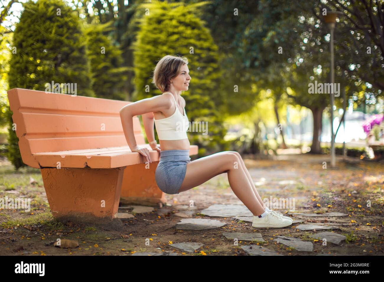 Ejercicio en el banco. Mujer entrenando en el parque. Concepto de salud y fitness Foto de stock