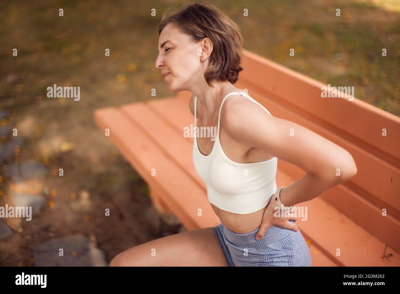 Mujer con dolor de espalda en el parque. Concepto de salud, salud y medicina Foto de stock