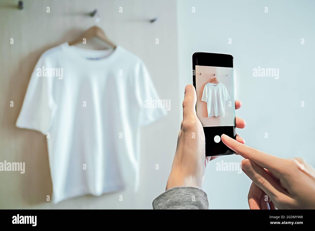 El hombre toma una foto en el smartphone de la ropa usada para la reventa Foto de stock