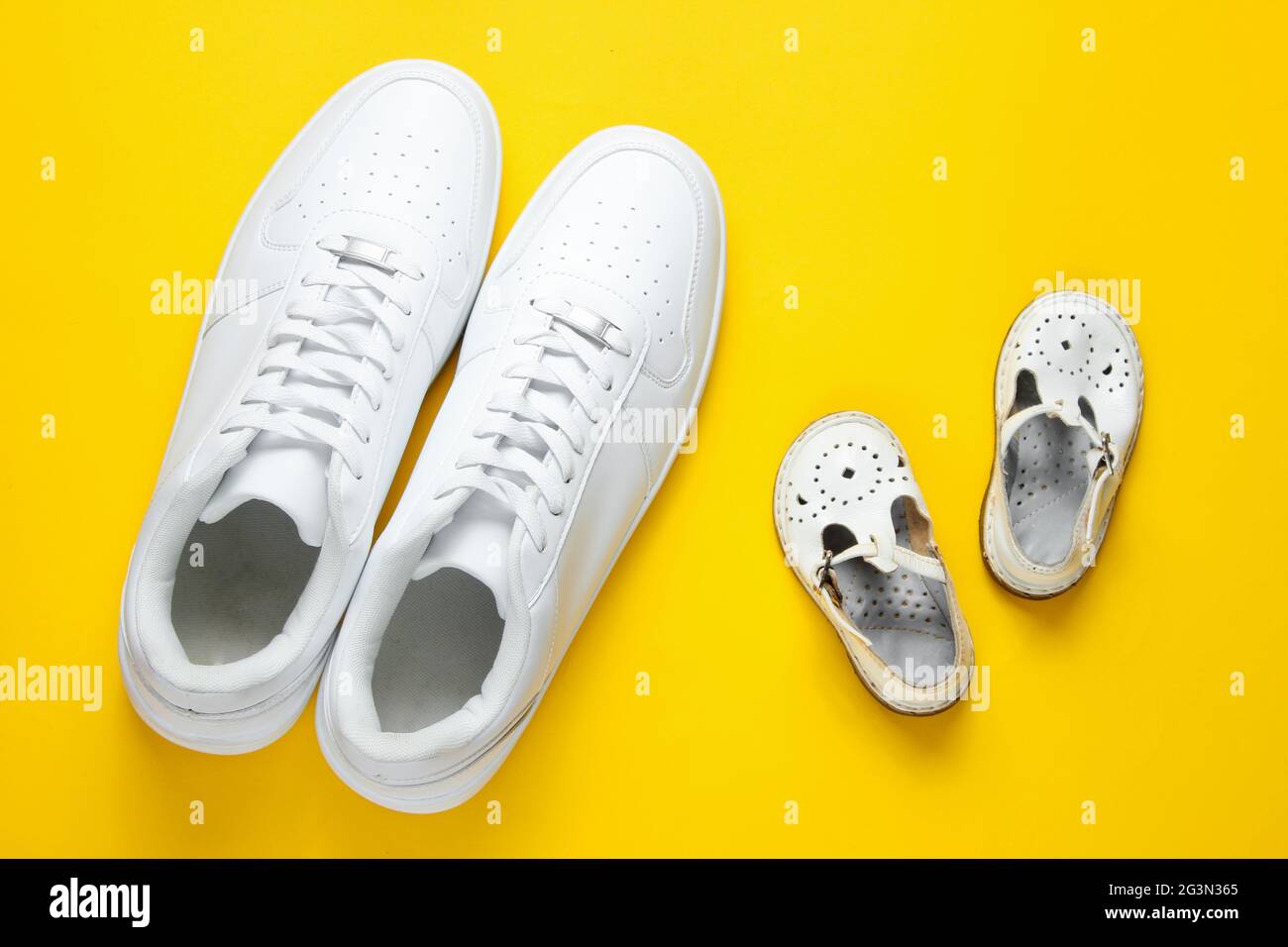 Concepto del día del padre. Zapatillas de lona blancas para adultos y  sandalias para niños sobre un fondo amarillo Fotografía de stock - Alamy