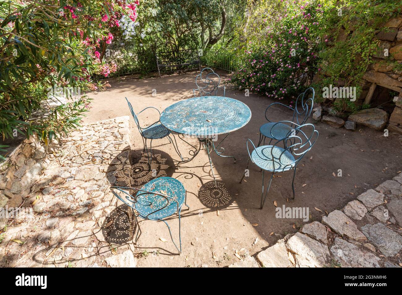 Mesa de hierro y sillas en un jardín público en el pueblo de Pigna. Córcega, Francia Foto de stock