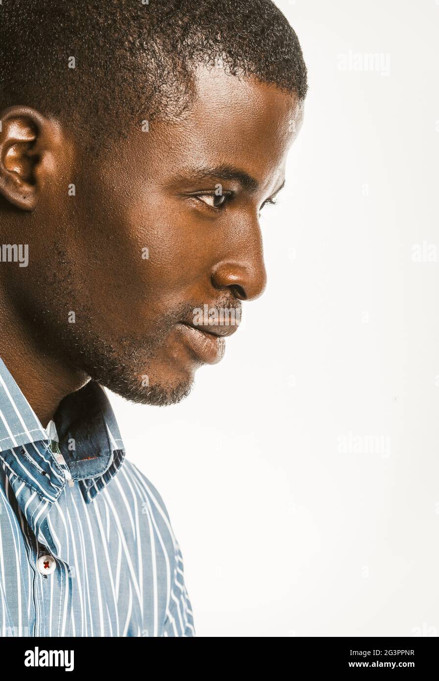 Vista de perfil del hombre afroamericano en una camisa de rayas azules. Retrato de primer plano de un atractivo hombre de piel oscura aislado en un Foto de stock