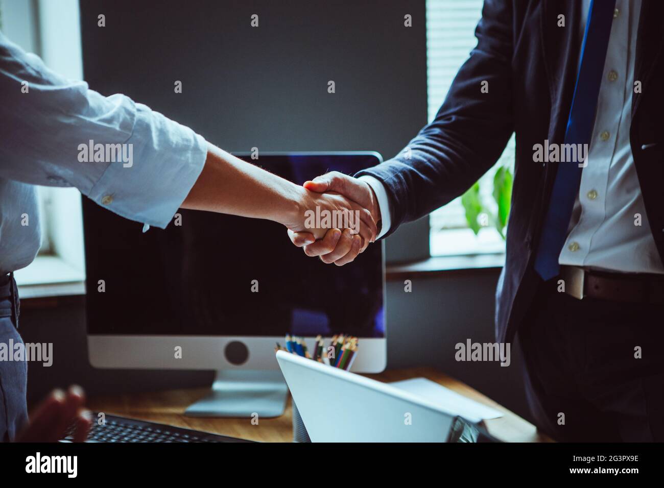 El hombre de negocios y la mujer de negocios sacuden las manos después de la lluvia de ideas del equipo. Foto de cerca de manos masculinas y femeninas contra la oficina int Foto de stock