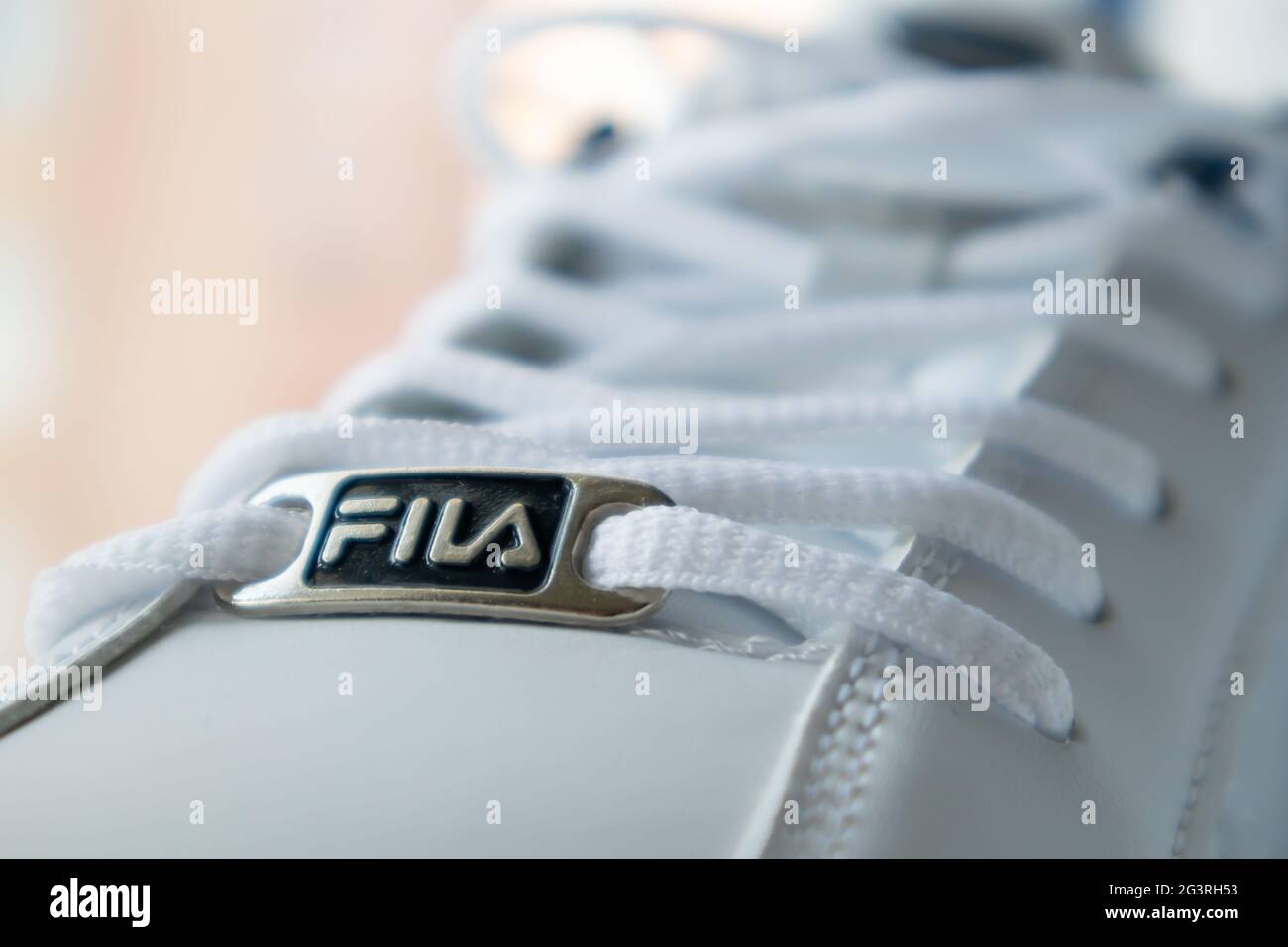 Zapatillas de lona atléticas blancas con cordones. Los cordones blancos  están atados en primer plano. Fondo borroso. Concepto deportivo. Famoso  logotipo de marca Fila. Moderno y con estilo Fotografía de stock -