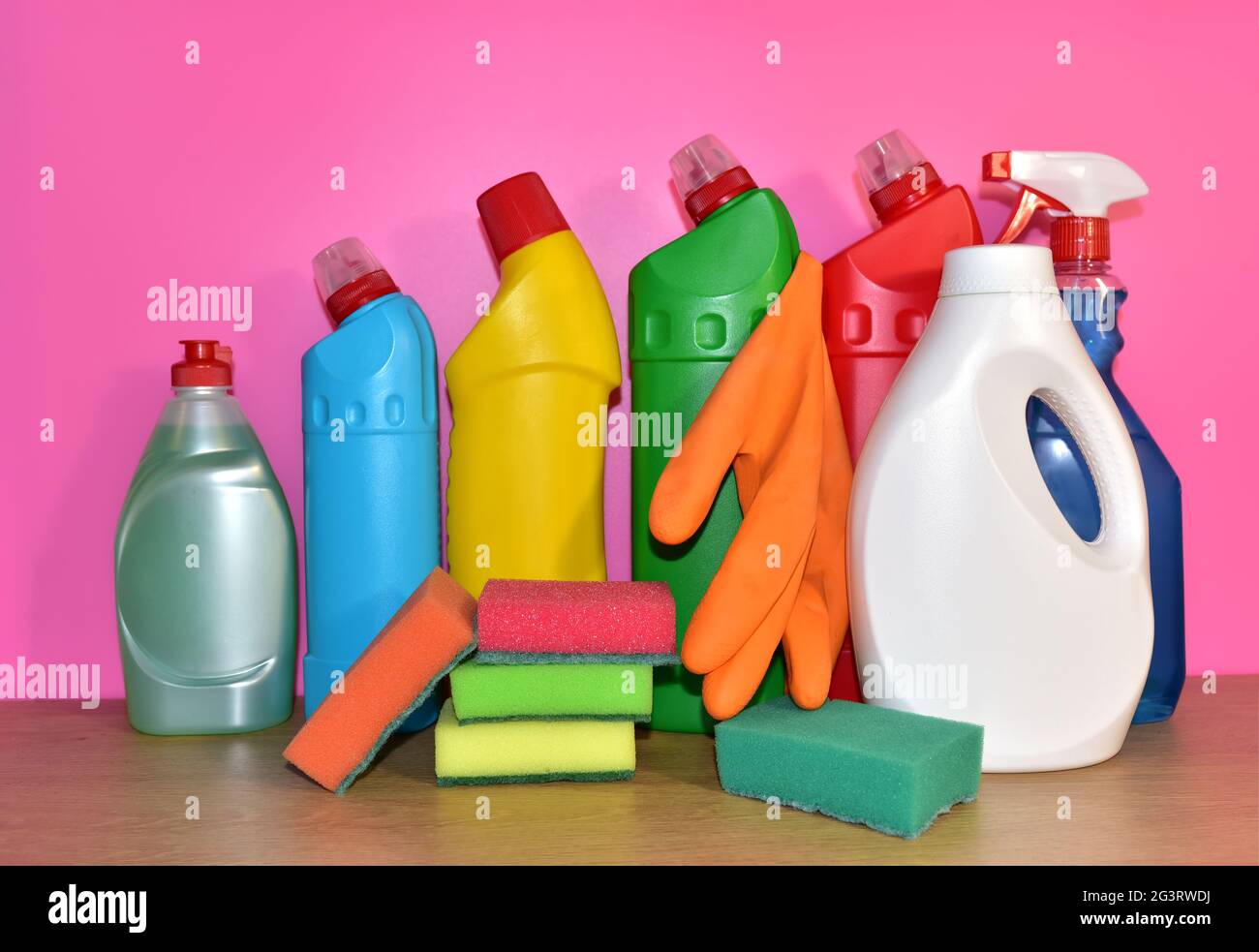 Botellas de detergente y esponja para lavar sobre fondo rosa