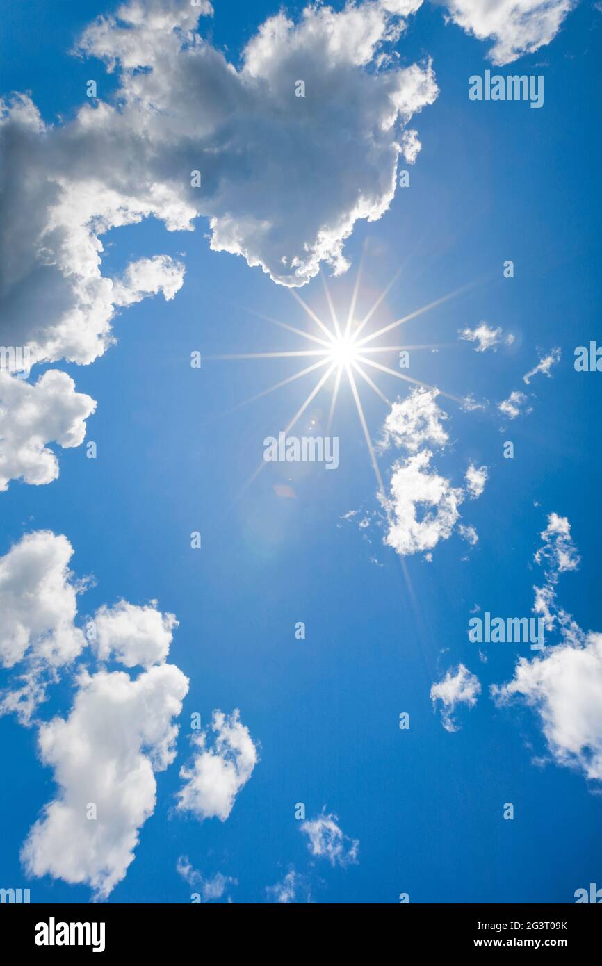 sol en el cielo azul con algunas nubes cúmulas en contraluz, Suiza Foto de stock