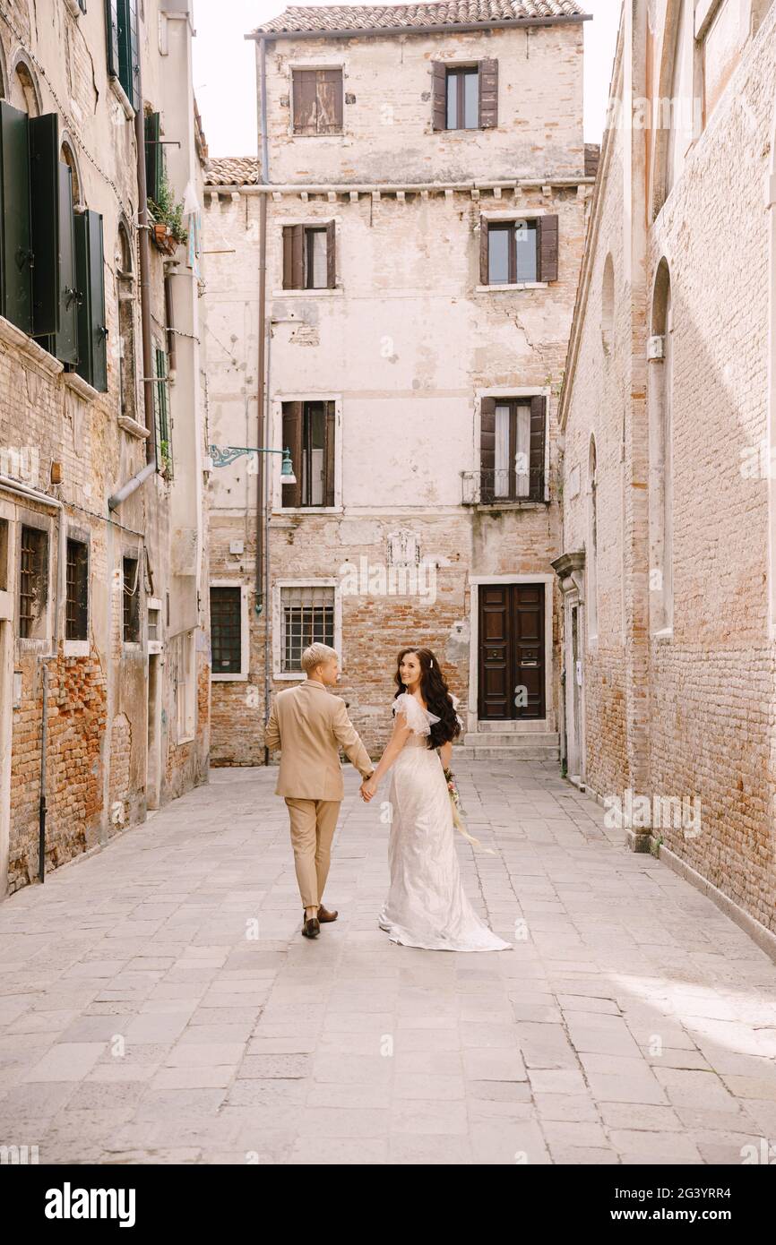 Italia boda en Venecia. La novia y el novio caminan a lo largo de las calles desiertas de la ciudad. Los recién casados están caminando en un callejón sin salida al Foto de stock