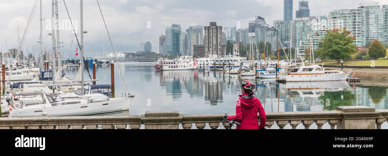 Mujer de Vancouver en el horizonte de la ciudad con casco de ciclismo en el puerto frente a la bandera panorámica de fondo urbano. Foto de stock